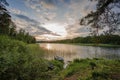 Sunset on the lake in Sweden. Green nature colors and blue sky with white clouds. Boat parked on shore.