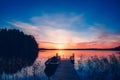 Sunset on a lake. Wooden pier with fishing boat at sunset in Finland Royalty Free Stock Photo