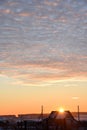 Sunset landscape in the countryside in winter. The setting sun behind the roof of the house in the evening. The disk of the sun Royalty Free Stock Photo