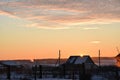 Sunset landscape in the countryside in winter. The setting sun behind the roof of the house in the evening. The disk of the sun Royalty Free Stock Photo
