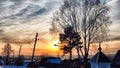 Sunset landscape in the countryside in winter. The setting sun behind the roof of the house in the evening. The disk of Royalty Free Stock Photo