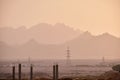 Sunset landscape with dark mountain peaks in egyptian desert and high voltage power lines Royalty Free Stock Photo