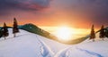 Sunset landscape with mountain hills and snowy valley with spruce trees under vibrant colorful evening sky in winter Royalty Free Stock Photo