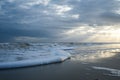 Sunset with Light Beams over the Ocean with Foamy Waves on the Beach Royalty Free Stock Photo