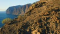 Sunset light illuminate steep Los Gigantes cliifs rocky barren volcanic mountains with dark blue deep ocean water. Sea