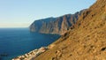 Sunset steep Los Gigantes cliifs rocky barren volcanic mountains with dark blue deep ocean water. Sea, crags silhouette