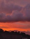 the sunset light is orange over the mountains and village trees