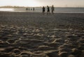 Sunset light over sandy beach with people walking Royalty Free Stock Photo