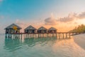 Maldives resort island villas, bungalows in sunset with wooden jetty, amazing colorful sky. Perfect sunset beach, summer vacation Royalty Free Stock Photo