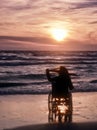 Sunset, makes sightseeing on the beach a woman on wheelchair