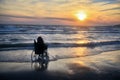 Sunset, makes sightseeing on the beach a woman on a wheelchair