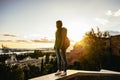 Sunset in Malaga, Spain. Young woman with backpack stands on a wall watching the horizon. Mediterrenean town and sea. Royalty Free Stock Photo