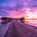 Sunset on Maldives island, luxury water villas resort and wooden pier. Beautiful sky and clouds and luxury beach background Royalty Free Stock Photo