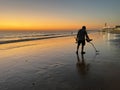 Sunset with man with metal detector on sandy beach Royalty Free Stock Photo