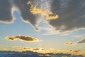 Sunset and mountain peaks. Cirrus and cumulus clouds with bright orange backlight against a blue sky. Royalty Free Stock Photo