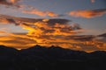 Sunset in the mountains, mountain silhouette against a cloudy sky in orange colors Royalty Free Stock Photo