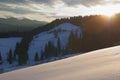 Sunset in the mountains. Snowy slope. Countryside in the woods Royalty Free Stock Photo