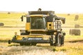 Sunset New Holland combine parked along a harvested field overlooking round bales of hay on the Canadian prairies. Royalty Free Stock Photo