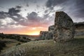 Sunset on the night of the summer solstice with a megalithic menhir in the foreground and a rocky mountain formation in the