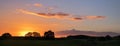 sunset with orange clouds over a wide rural landscape with meadows and trees, panorama format with copy space Royalty Free Stock Photo