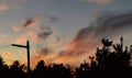 sunset with orange clouds and silhouettes of trees and plants in backlight and electricity pole Royalty Free Stock Photo