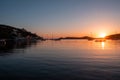 Sunset orange color over sea water. Boats anchored at Vourkari port, Kea island, Greece