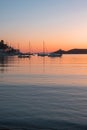 Sunset orange color over sea water. Boats anchored at Vourkari port, Kea island, Greece