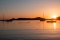 Sunset orange color over sea water. Boats anchored at Vourkari port, Kea island, Greece