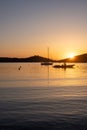 Sunset orange color over sea water. Boats anchored at Vourkari port, Kea island, Greece