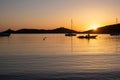 Sunset orange color over sea water. Boats anchored at Vourkari port, Kea island, Greece