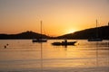 Sunset orange color over sea water. Boats anchored at Vourkari port, Kea island, Greece