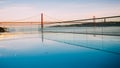 Sunset over the `25 of April` Bridge in Lisbon, Portugal with reflection from infinity pool Royalty Free Stock Photo