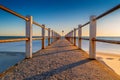 Sunset over beach, ocean and concrete pier or jetty Royalty Free Stock Photo