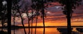 Sunset over a beautiful lake through silhouette of trees and boats Royalty Free Stock Photo