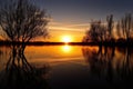 sunset over calm lake, with water reflections and silhouettes of trees