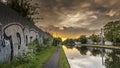 Sunset over a canal, with a graffiti covered waqll in the foreground