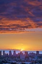 A sunset over a city skyline near the sea with cloudy purple and orange sky. Sunrise over a blue horizon near urban Royalty Free Stock Photo