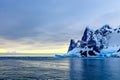 Sunset over cliffs, blue glacier and drifting iceberg with water