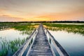 Sunset over coastal waters with a very long wooden boardwalk