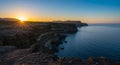 Sunset over dramatic cliffs, possibly in Ireland, with rugged layers of rock descending Royalty Free Stock Photo