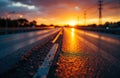 Sunset over an empty highway with reflective wet road surface and distant power Royalty Free Stock Photo