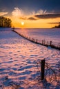 Sunset over a fence in a snow covered farm field in rural Carroll County, Maryland. Royalty Free Stock Photo