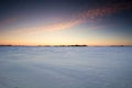 Sunset over a frozen snow covered field.