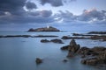 Sunset over Godrevy Lighthouse on Godrevy Island in St Ives Bay with the beach and rocks in foreground, Cornwall UK