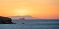 Sunset over Greek island as line ship leaves Cyclades. Sun colors the sky. Blue Aegean sea. Space Royalty Free Stock Photo