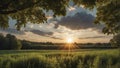 a sunset over a green field with the sun shining through the clouds, wind moving green grass Royalty Free Stock Photo