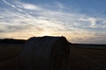 Sunset over harvested field with round bales of straw.