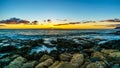 Sunset over the horizon with a few clouds and the rocky shores of the west coast of Oahu Royalty Free Stock Photo