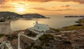 Greece, Kea Tzia island. Small white church on a rocky hill, over Korissia port at sunset