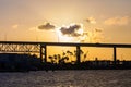 Sunset over lagoon with silhouette of bridge and palm tress